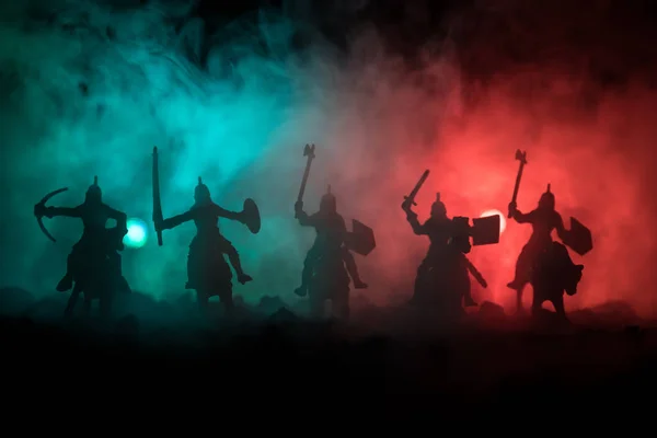 Escena de batalla medieval con caballería e infantería. Siluetas de figuras como objetos separados, lucha entre guerreros sobre fondo de niebla tonificado oscuro. Escena nocturna . —  Fotos de Stock