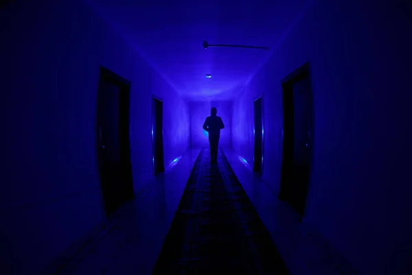 Жуткий силуэт в темном заброшенном здании. Темный коридор с дверями шкафа и огнями с силуэтом жуткого человека ужаса, стоящего в разных позах . — стоковое фото