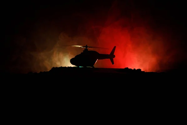 Silhouette d'hélicoptère militaire prêt à décoller de la zone de conflit. Images de nuit décorées avec hélicoptère commençant dans le désert avec rétroéclairage tonique brumeux. Concentration sélective . — Photo