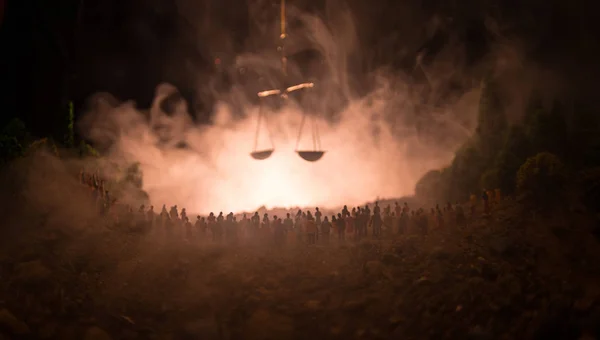Sylwetka niewyraźne olbrzymie skali sprawiedliwości za tłum w nocy z ognia mglisty tło. — Zdjęcie stockowe