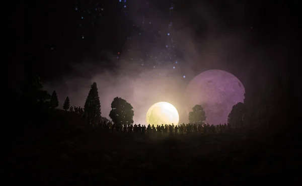 Silhouet van een grote menigte van mensen in bos kijken bij stijgende grote volle maan 's nachts. Ingericht achtergrond met nachtelijke hemel met sterren, maan- en ruimte-elementen. Selectieve aandacht. — Stockfoto