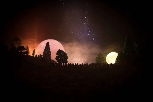 Silhuetten av en stor skara människor i skogen på kvällen titta på stigande stor fullmåne. Inredda bakgrund med natthimlen med stjärnor, måne och utrymme element. Selektivt fokus. — Stockfoto