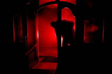 Kapalı cam bir kapıdan geçen, bilinmeyen bir gölge figürünün silueti. Geceleri pencerenin önündeki bir insanın silueti. Manyağın bulanık silueti korkunç cadılar bayramı konsepti.