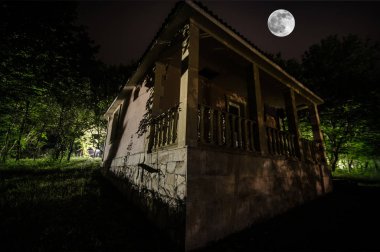 Orman, binada sisli gece moon ile dağ gece manzarası. Yeşil çayır, büyük ağaçlar ve terk edilmiş evde gece. Gece çekimi