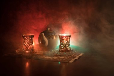 Geleneksel glasse ve ışıklar ve duman siyah zemin üzerine pot Doğu tea. Doğu çay kavramı. Armudu geleneksel Azerbaycan/Türkiye Kupası. Seçici odak. Bardak çay