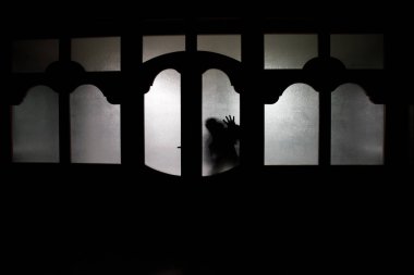 Bir bilinmeyen gölge figürü bir kapı bir kapalı cam kapıdan silüeti. Geceleri bir pencerenin önünde bir insan silüeti. Korkunç sahne Cadılar Bayramı kavramı bulanık silueti