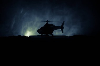 Askeri helikopter çatışma bölgesinden uçmaya hazır silüeti. Gece görüntüleri çöl sisli tonda sırt ile başlayarak helikopter ile dekore edilmiştir. Seçici odak.