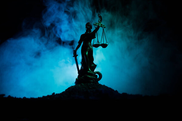 The Statue of Justice - lady justice or Iustitia / Justitia the Roman goddess of Justice on a dark fire background. Selective focus