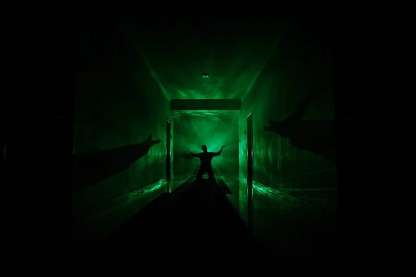 Griezelig silhouet in de donkere verlaten gebouw. Donkere gang met kabinetsdeuren en verlichting met silhouet van spooky horror persoon permanent met verschillende poses. — Stockfoto