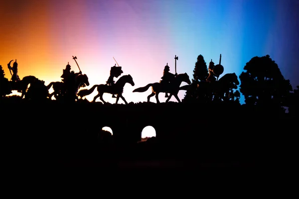 Średniowieczne bitwy scena na moście z kawalerii i piechoty. Sylwetki postaci jako oddzielne obiekty, walka pomiędzy wojowników na ciemny stonowanych mglisty tło. Scena nocy. — Zdjęcie stockowe
