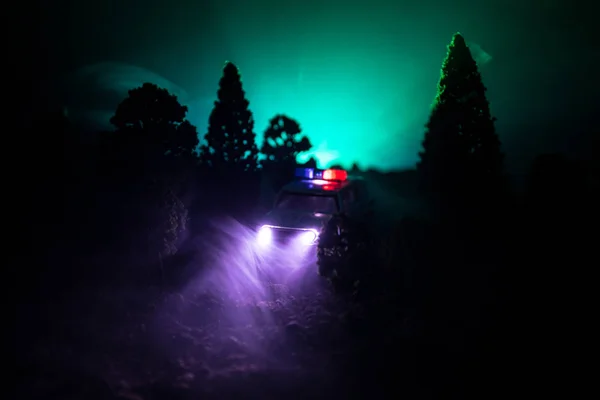 Rendőrautó üldöz egy kocsit éjszaka, ködös háttérrel. 911 Sürgősségi segélyhívó rendőrautó száguld a tetthelyre.. — Stock Fotó