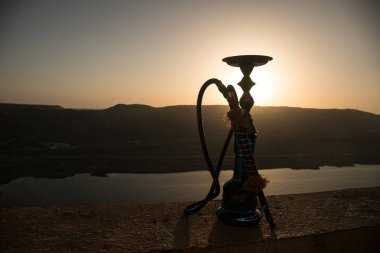 Nargile, geleneksel Arapça harcamak, doğrudan günbatımı güneş ışığı, açık fotoğraf. Dağ arka plan veya nargile günbatımı arka plan üzerinde siluetleri. Açık.