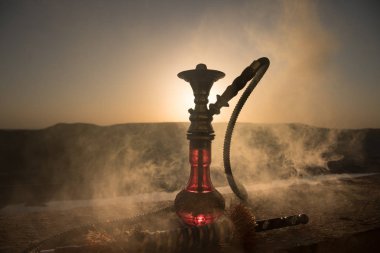 Nargile, geleneksel Arapça harcamak, doğrudan günbatımı güneş ışığı, açık fotoğraf. Dağ arka plan veya nargile günbatımı arka plan üzerinde siluetleri. Açık.