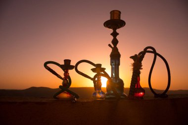 Nargile, geleneksel Arapça harcamak, doğrudan günbatımı güneş ışığı, açık fotoğraf. Dağ arka plan veya nargile günbatımı arka plan üzerinde siluetleri. Açık.