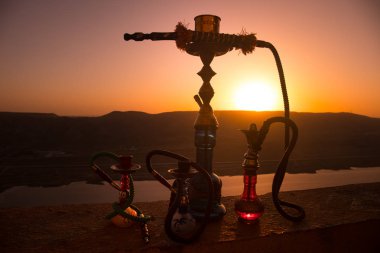 Nargile, geleneksel Arapça harcamak, doğrudan günbatımı güneş ışığı, açık fotoğraf. Dağ arka plan veya nargile günbatımı arka plan üzerinde siluetleri. Açık.