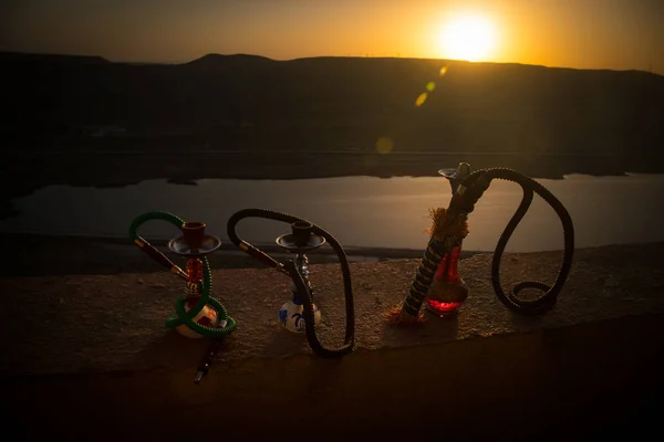 Hookah, tradicional cachimbo de água árabe, luz direta do pôr do sol, foto ao ar livre. Fundo da montanha ou silhuetas de narguilé no fundo do pôr do sol. Ao ar livre . — Fotografia de Stock