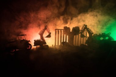 Bir şehir sokak inşaatta. Bir sarı kazıcı ekskavatör bir inşaatta gece boyunca park. Endüstriyel kavramı masa dekorasyonu Karanlık sisli tonlu arka plan üzerinde