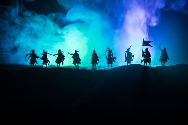 Süvari ve piyade ile ortaçağ savaş sahnesi. Siluetleri şekiller ayrı nesneler olarak mücadele koyu tonda sisli arka plan savaşçılar arasında. Gece çekimi.