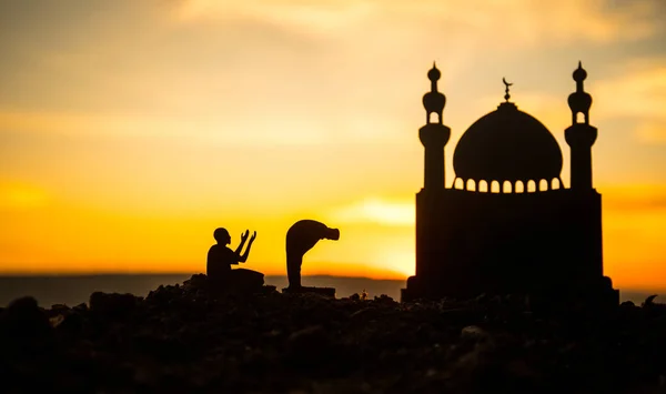 Concept of religion Islam. Silhouette of man praying on the background of a mosque at sunset — Stock Photo, Image