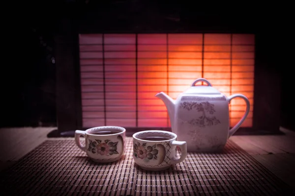 Concepto de té. Ceremonia del té japonés cultura bebida oriental. Tetera y tazas en la mesa con hojas de bambú al atardecer — Foto de Stock