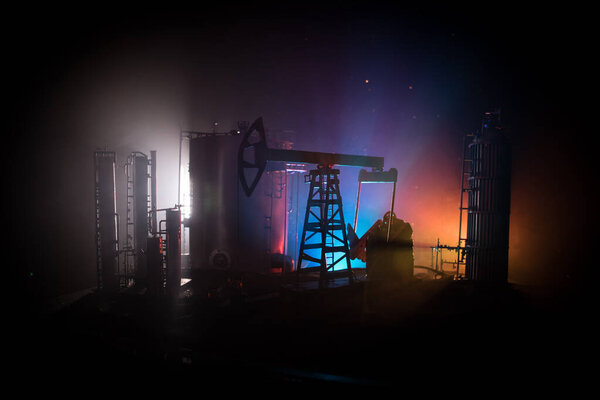 Художественное оформление. Нефтяной насос и нефтяная вышка энергетические промышленные машины для нефти ночью с туманом и подсветкой. Нефтеперерабатывающий завод. Энергетическая промышленная концепция. Селективный фокус
