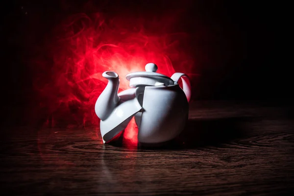 在暗色调的雾背景上破碎的茶壶。木桌上的陶瓷茶壶. — 图库照片
