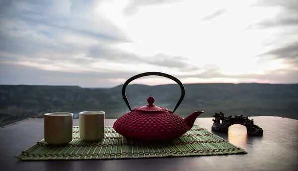 Tea concept. Japanese tea ceremony culture east beverage. Teapot and cups on table with bamboo leaves on sunset — Stock Photo, Image