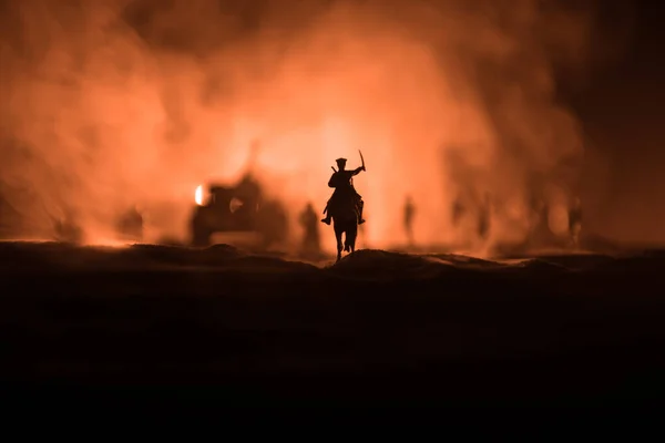 Oficial de guerra mundial (ou guerreiro) cavaleiro a cavalo com uma espada pronta para lutar e soldados em um fundo enevoado escuro. Batalha campo de batalha cena de soldados de combate . — Fotografia de Stock