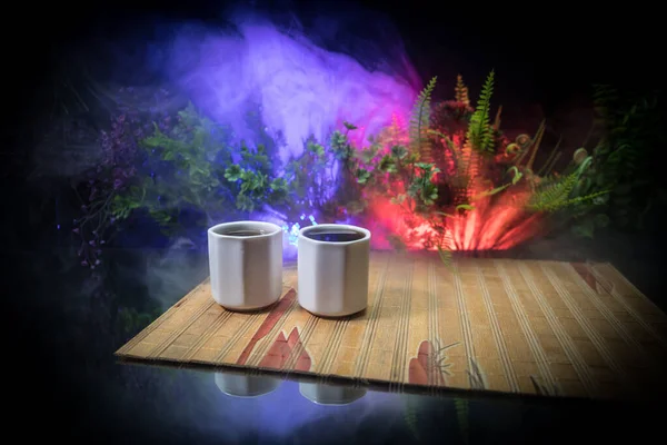 Tea concept. Japanese tea ceremony culture east beverage. Teapot and cups on table with bamboo leaves on sunset