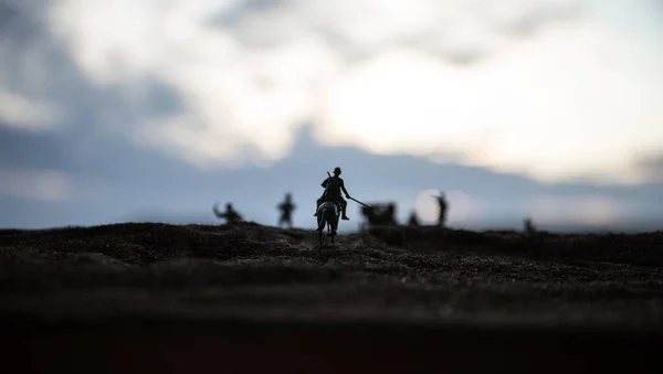 Oficial de guerra mundial (ou guerreiro) cavaleiro a cavalo com uma espada pronta para lutar e soldados em um fundo enevoado escuro. Batalha campo de batalha cena de soldados de combate . — Fotografia de Stock