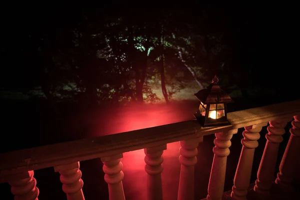 Retro style lantern at night. Beautiful colorful illuminated lamp at the balcony in the garden.