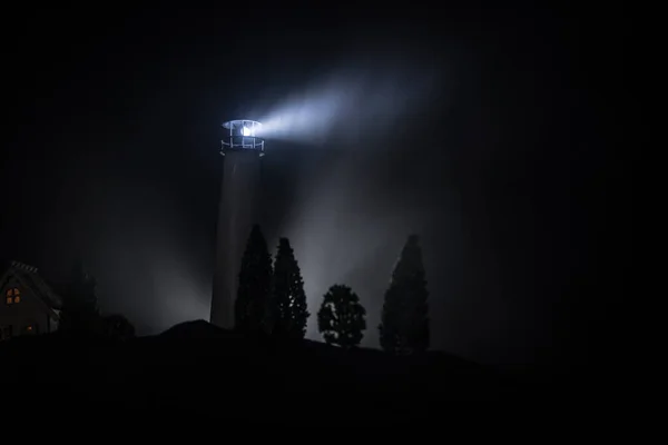 霧の夜の光のビームを持つ灯台。山に古い灯台の立っています。テーブル デコレーション。トーンの背景。こちらブルームーン探偵社. — ストック写真