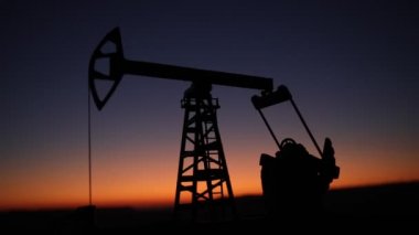 Gün batımında petrol pompası ve petrol rafineri fabrikasının siluet görüntüleri