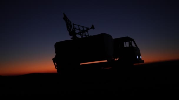 日没時にレーダーアンテナを備えた移動式防空トラックのシルエット映像 — ストック動画
