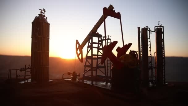 日没時の石油ポンプと石油精製工場のシルエット — ストック動画