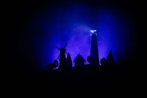 Маяк со световым лучом ночью с туманом. Старый маяк стоит на горе. Украшение стола. Тонированное прошлое. Лунный свет . — стоковое фото
