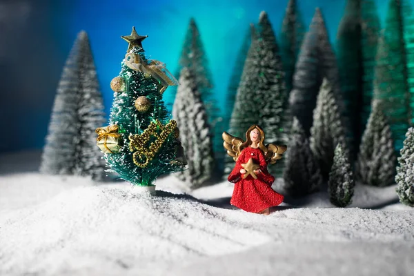 Little white guardian angel in snow. Festive background. Christmas decorations.