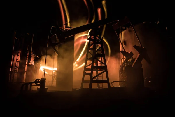 Decoração de obras de arte. Bomba de óleo e equipamento de óleo máquinas industriais de energia para petróleo à noite com nevoeiro e luz de fundo. Fábrica de refinação de petróleo. Conceito industrial de energia. Foco seletivo — Fotografia de Stock