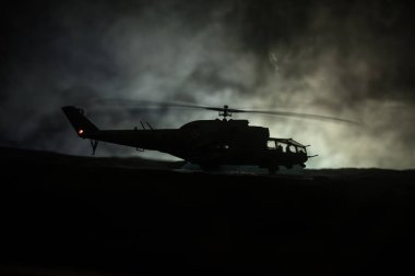 Askeri helikopter çatışma bölgesinden uçmaya hazır silüeti. Gece görüntüleri çöl sisli tonda sırt ile başlayarak helikopter ile dekore edilmiştir. Seçici odak.