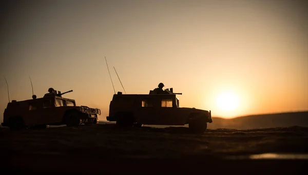 Militärpatrouillenwagen im Hintergrund des Sonnenuntergangs. Heereskriegskonzept. Silhouette eines gepanzerten Fahrzeugs mit angriffsbereiten Soldaten. Kunstwerk Dekoration. Selektiver Fokus — Stockfoto