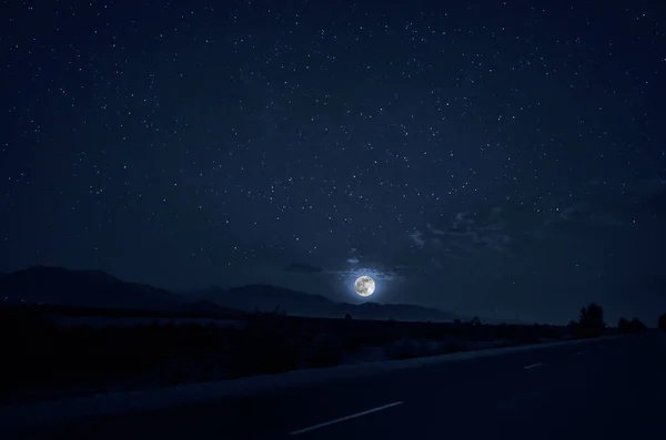 Довга стрілянина. Гірська дорога через ліс у повний місяць. Сценічний нічний пейзаж темно-синього неба з місяцем. Азербайджан — стокове фото