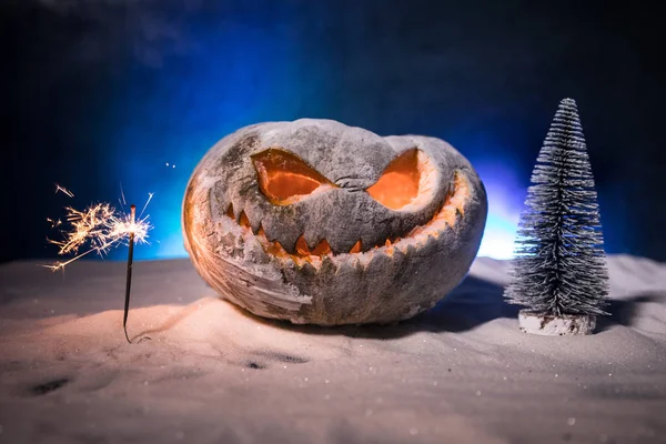 Yılbaşı ya da Cadılar Bayramı Arkaplanını Bulanık Bokeh Kar Arkaplanındaki Küçük Noel Ağacı ile Korkunç Balkabağıyla Kutla — Stok fotoğraf