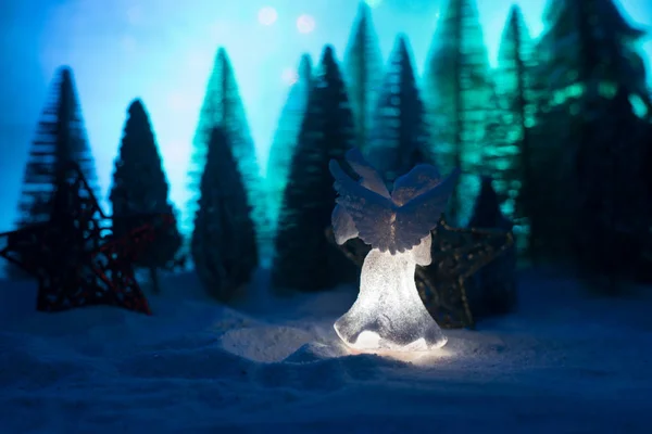 Little white guardian angel in snow. Festive background. Christmas decorations.