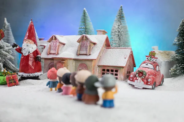 Kerst- en nieuwjaarsvakantie concept. Kleine decoratieve schattige huisjes in de sneeuw 's nachts in de winter, Fir boom staat op sneeuw met mooie vakantie versierde achtergrond — Stockfoto