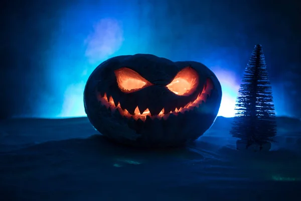 Christmas New Year or Halloween Celebrate Background with Little Christmas Tree on Blurred Bokeh Snow Background with horror pumpkin