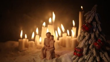 Yanan mumlar ve birkaç figürle birlikte Noel kompozisyonunun yakın çekim görüntüleri.