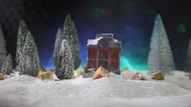 Oyuncak ev ve köknar ağaçlarının renkli ışıklar altında olduğu Noel kompozisyonunun yakın çekim görüntüleri.