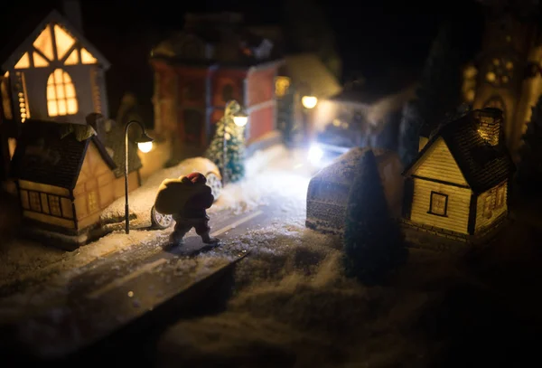 Nieuwjaar miniatuur huis in de sneeuw 's nachts met dennenboom. Vakantie concept. Selectieve focus — Stockfoto
