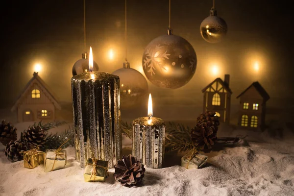 Decorazione artistica creativa. Decorazione natalizia con candele accese su sfondo scuro. Ornamenti natalizi su sfondo dorato scuro con luci . — Foto Stock