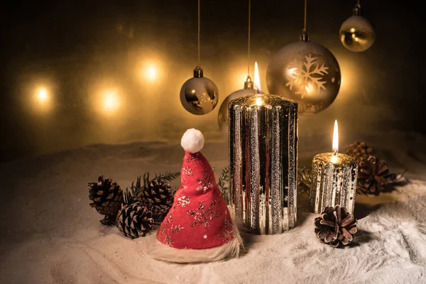 Decoración artística creativa. Decoración navideña con velas encendidas sobre un fondo oscuro. Adornos navideños sobre fondo dorado oscuro con luces . — Foto de Stock